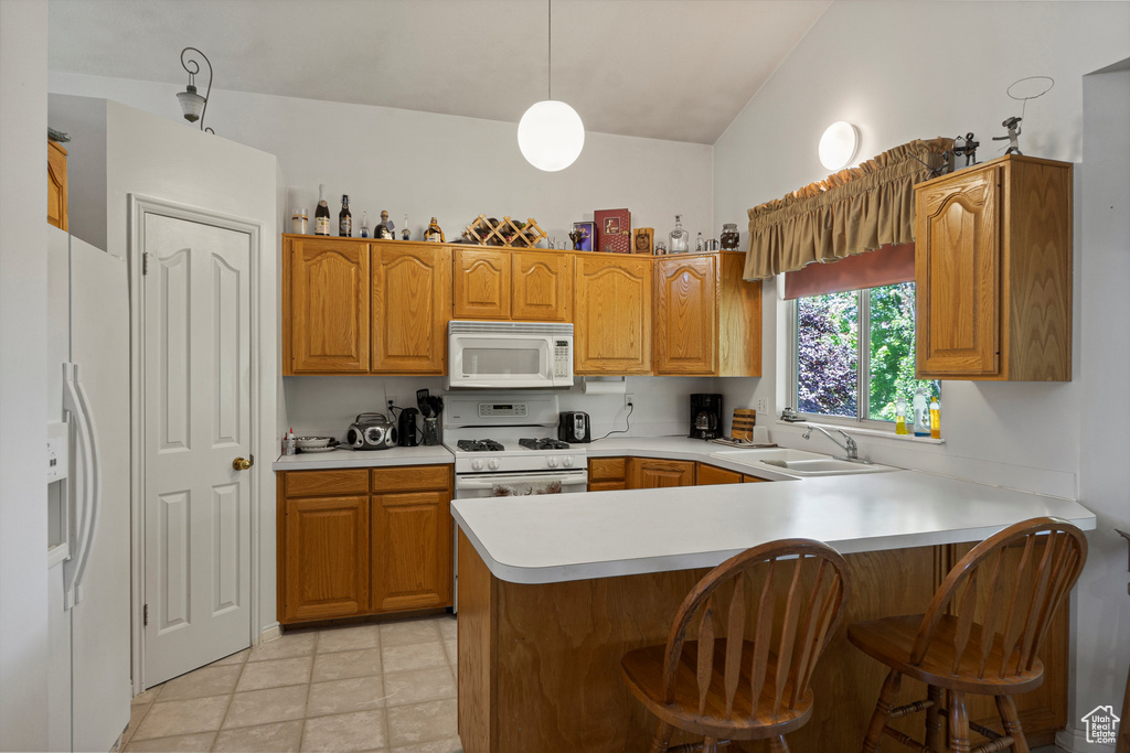 Kitchen with white appliances, a sink, a peninsula, light countertops, and lofted ceiling