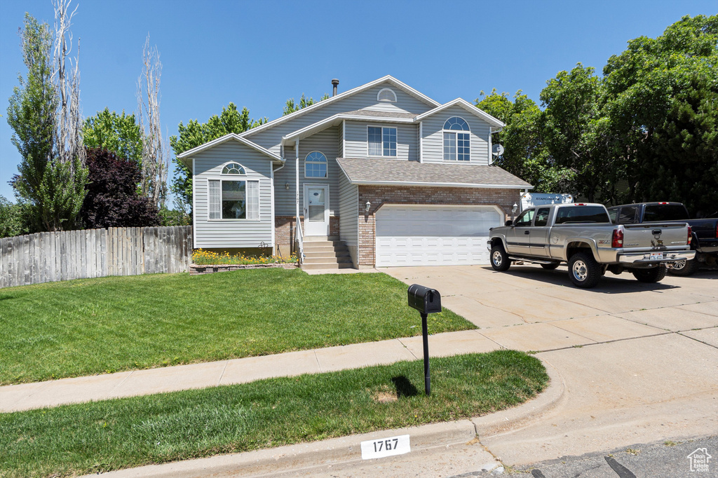 View of front of property featuring an attached garage, concrete driveway, and brick siding