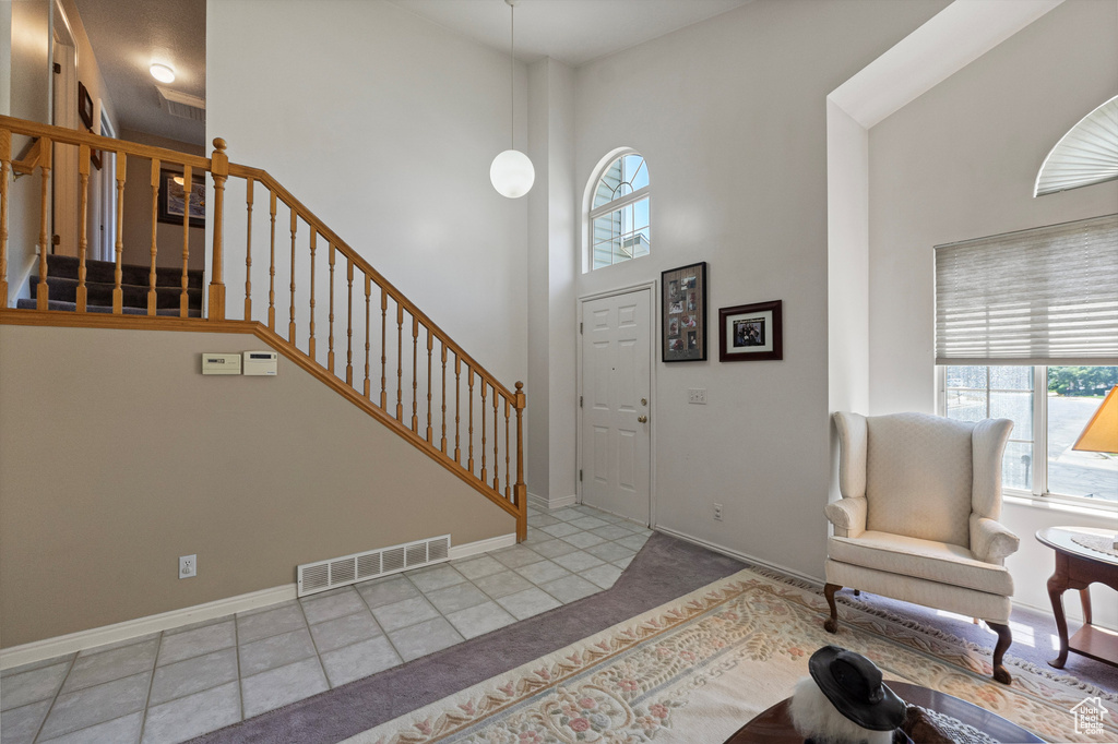Entrance foyer featuring plenty of natural light, a towering ceiling, stairway, baseboards, and carpet
