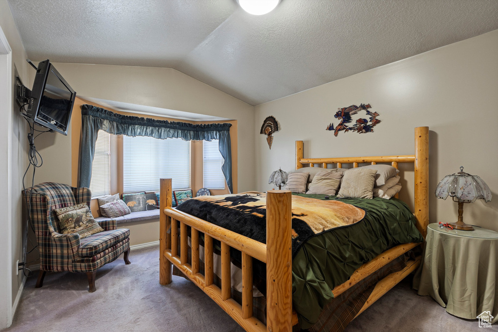 Bedroom with vaulted ceiling, carpet flooring, and a textured ceiling