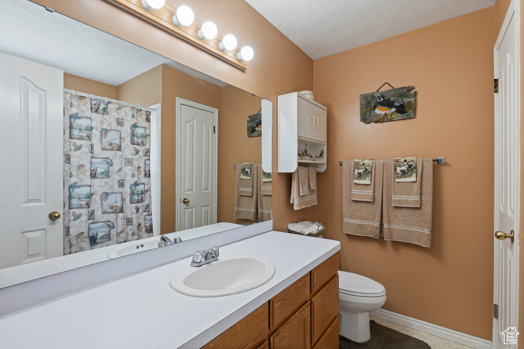 Full bathroom with toilet, vanity, baseboards, a shower with curtain, and tile patterned floors