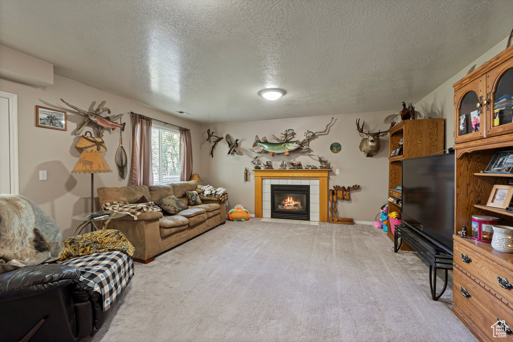 Carpeted living area with a textured ceiling and a tiled fireplace