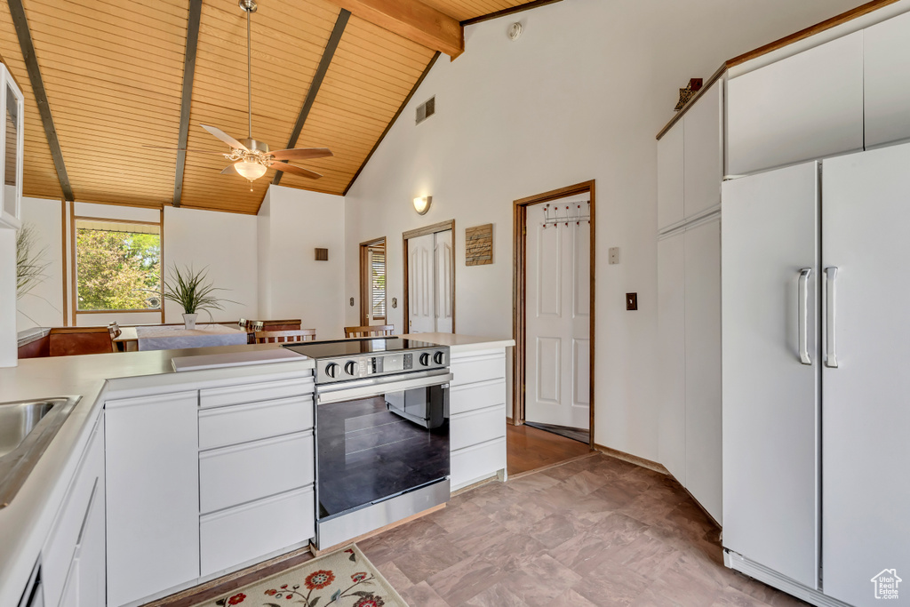 Kitchen featuring freestanding refrigerator, stainless steel electric stove, wooden ceiling with exposed beams, high vaulted ceiling, and a ceiling fan