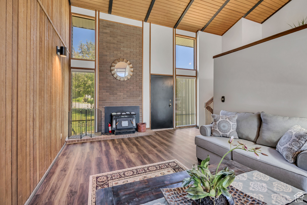 Living room featuring high vaulted ceiling, wooden ceiling with exposed beams, healthy amount of natural light, wood finished floors, and wooden walls
