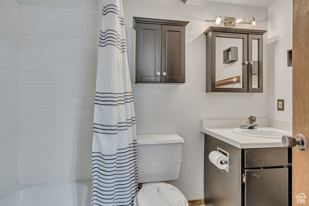 Bathroom featuring toilet, vanity, and shower / bath combo with shower curtain