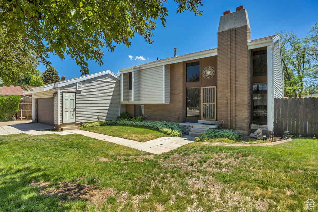 Mid-century modern home with a chimney, brick siding, entry steps, an attached garage, and driveway