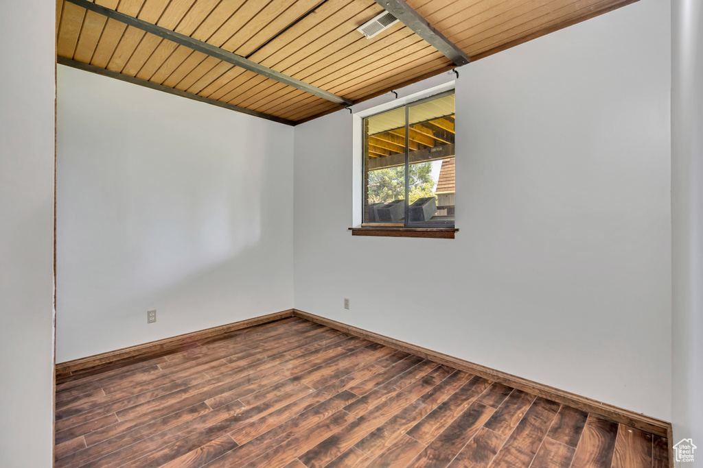 Empty room featuring wood finished floors, baseboards, and wood ceiling with exposed beams