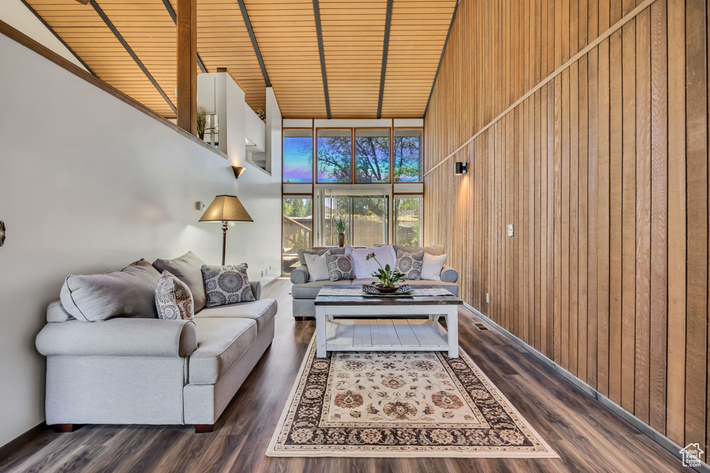 Living room featuring wooden ceiling with exposed beams, wood walls, high vaulted ceiling, wood finished floors, and expansive windows