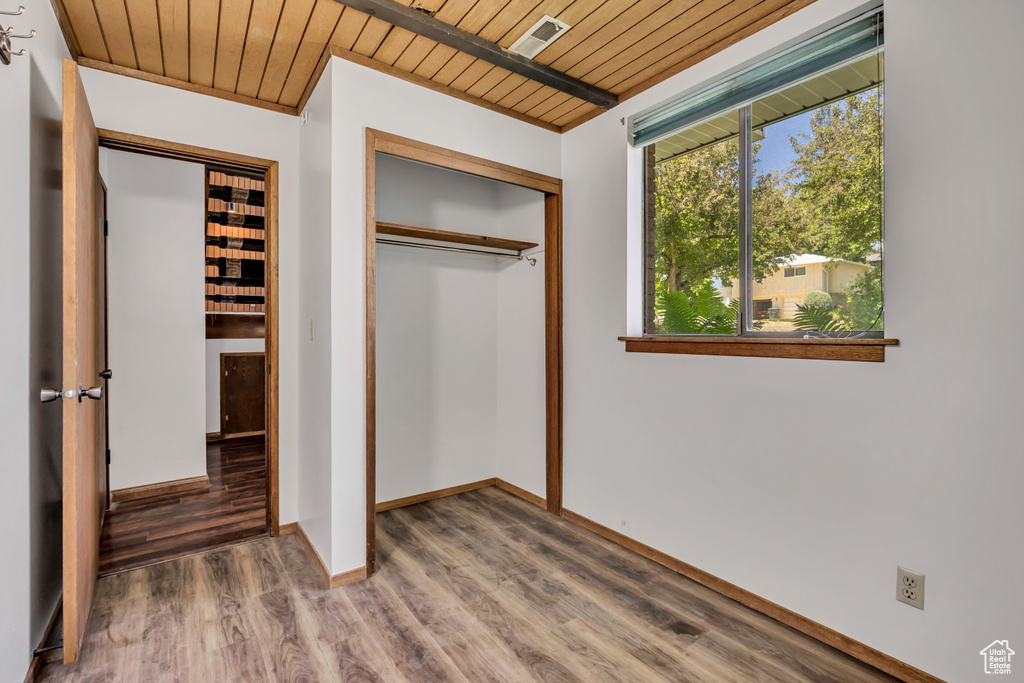 Unfurnished bedroom featuring wood ceiling, a closet, wood finished floors, and baseboards