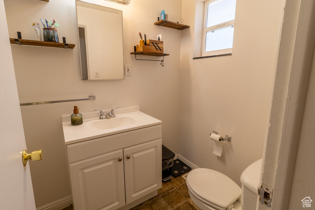 Half bathroom with vanity, toilet, and baseboards