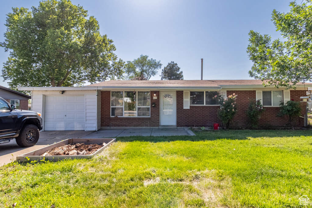 Single story home featuring a garage, brick siding, and a front yard