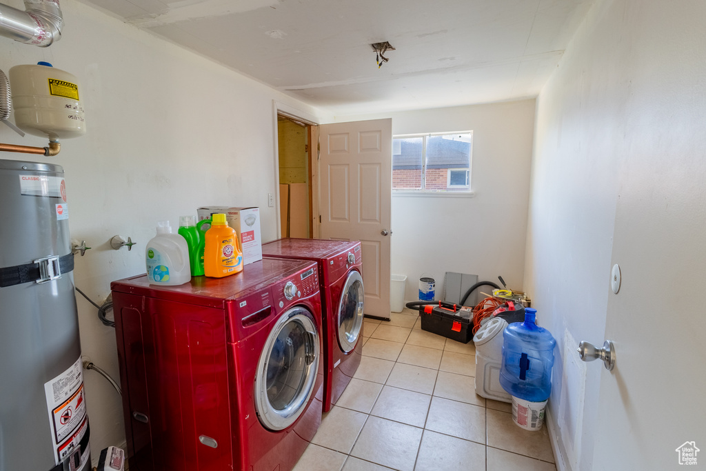 Washroom featuring water heater, washing machine and dryer, and light tile patterned floors