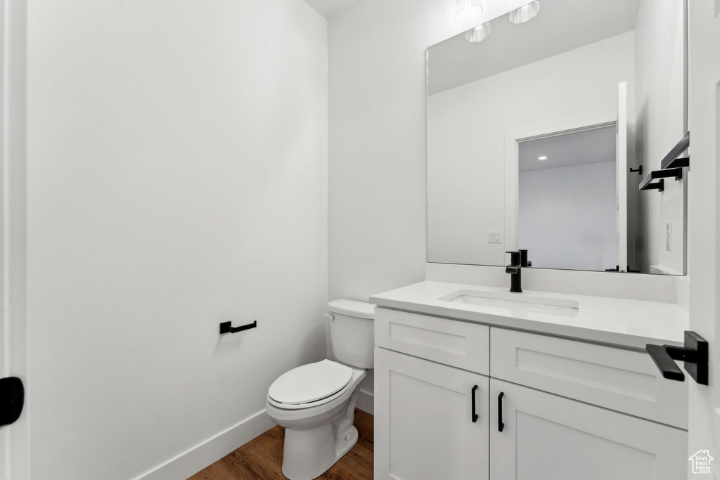 Bathroom featuring wood finished floors, vanity, toilet, and baseboards