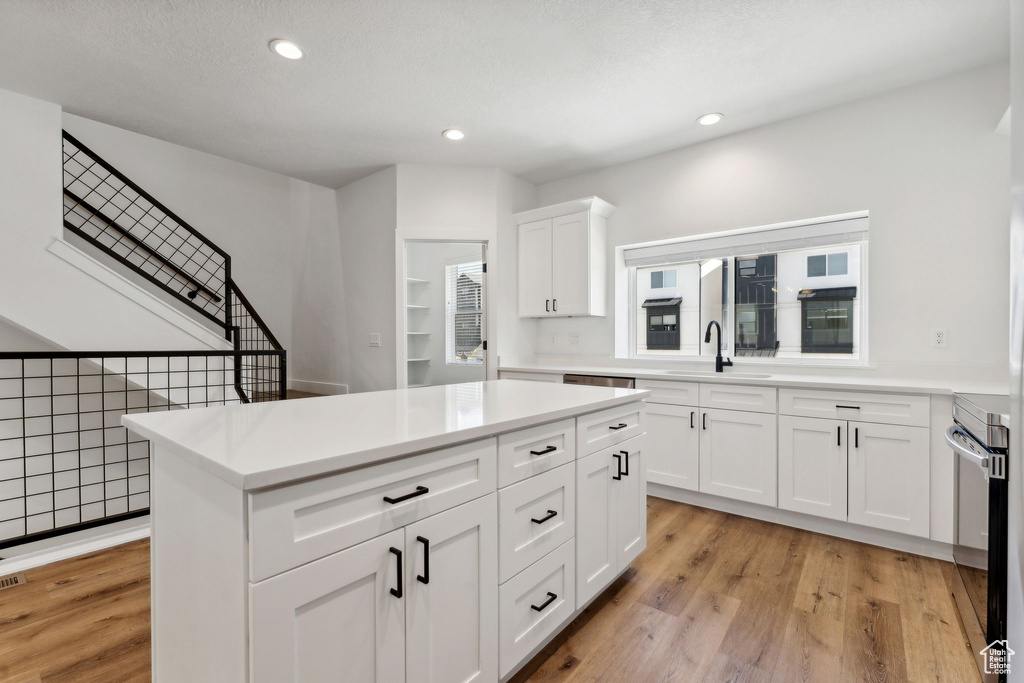 Kitchen featuring a sink, light wood-type flooring, recessed lighting, light countertops, and white cabinets