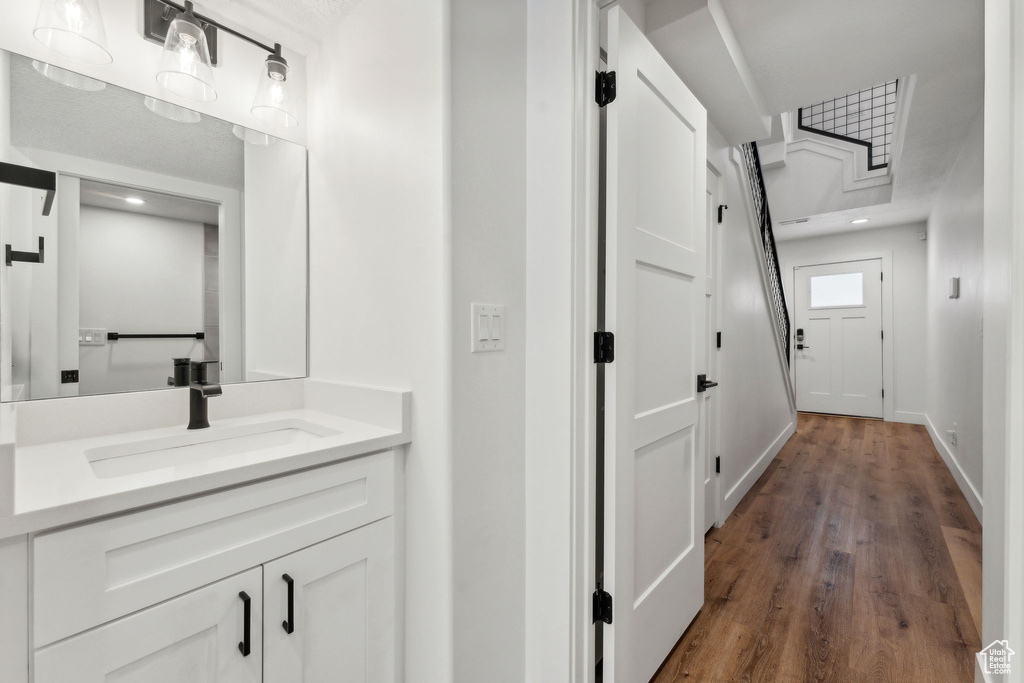Bathroom featuring vanity, wood finished floors, baseboards, and recessed lighting