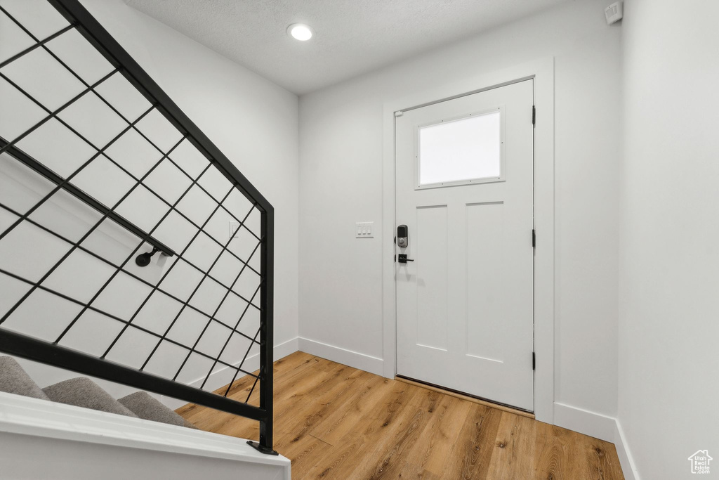 Entrance foyer featuring baseboards, stairway, light wood-style floors, and recessed lighting