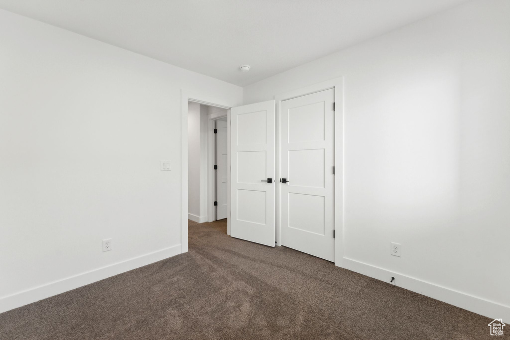 Unfurnished bedroom with carpet flooring and baseboards