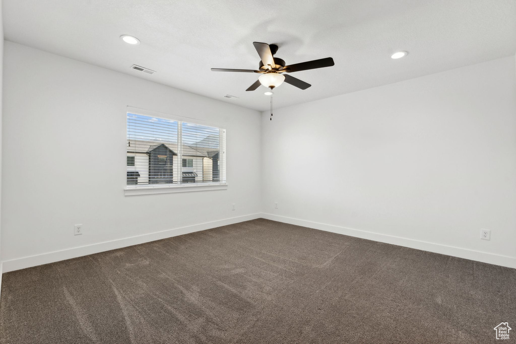 Empty room with ceiling fan, dark carpet, baseboards, and recessed lighting