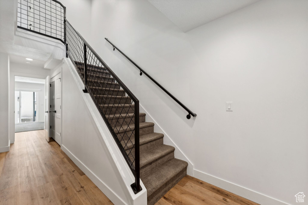 Stairway with wood finished floors and baseboards