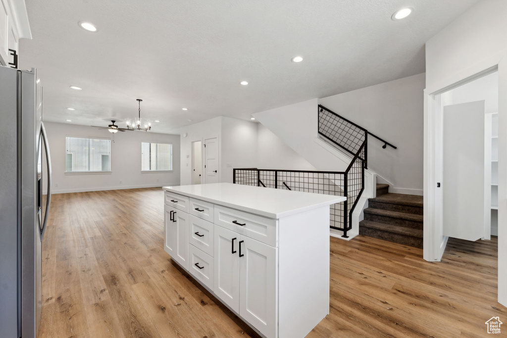 Kitchen featuring freestanding refrigerator, open floor plan, light wood-style floors, a chandelier, and white cabinetry
