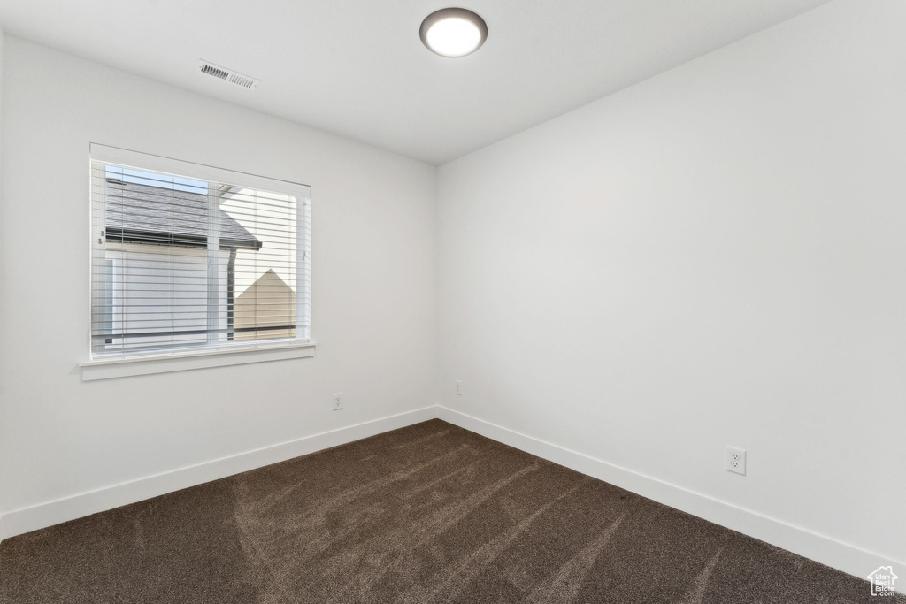 Unfurnished room featuring baseboards and dark colored carpet
