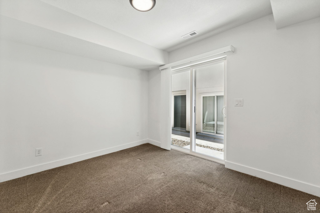Spare room with dark colored carpet and baseboards