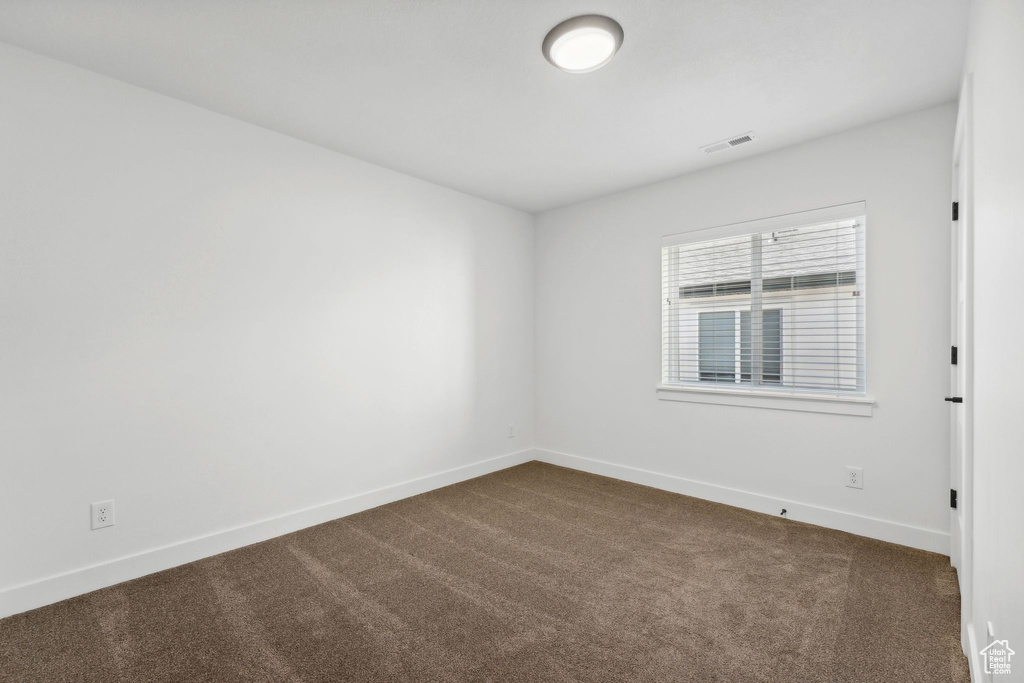 Spare room featuring baseboards and dark carpet