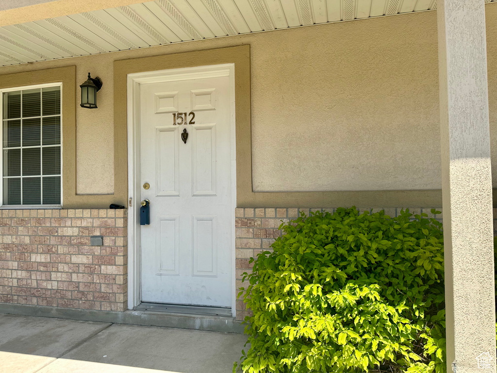 Doorway to property with brick siding and stucco siding