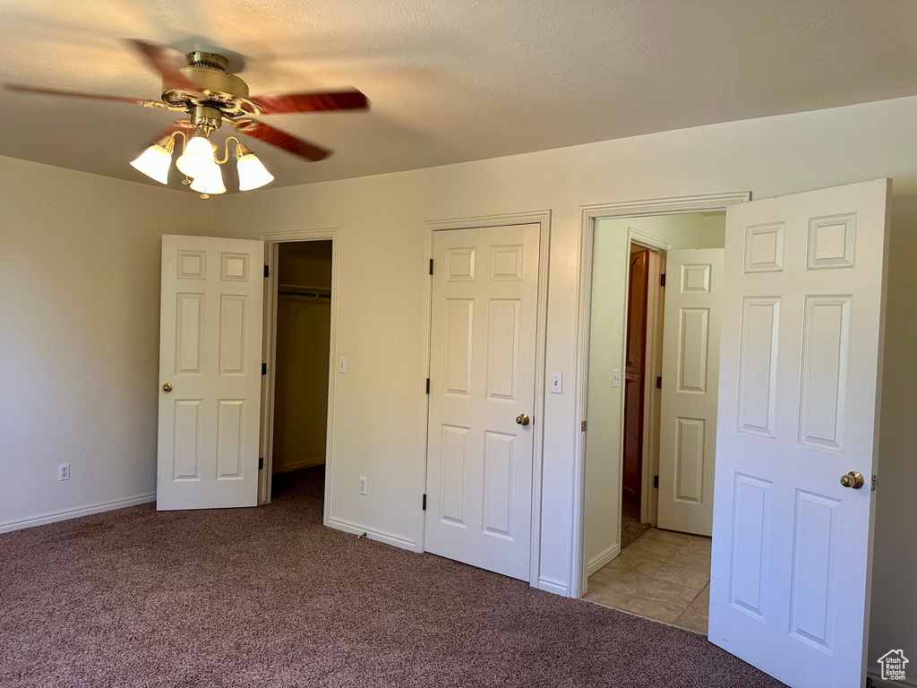 Unfurnished bedroom featuring carpet, a ceiling fan, and a spacious closet