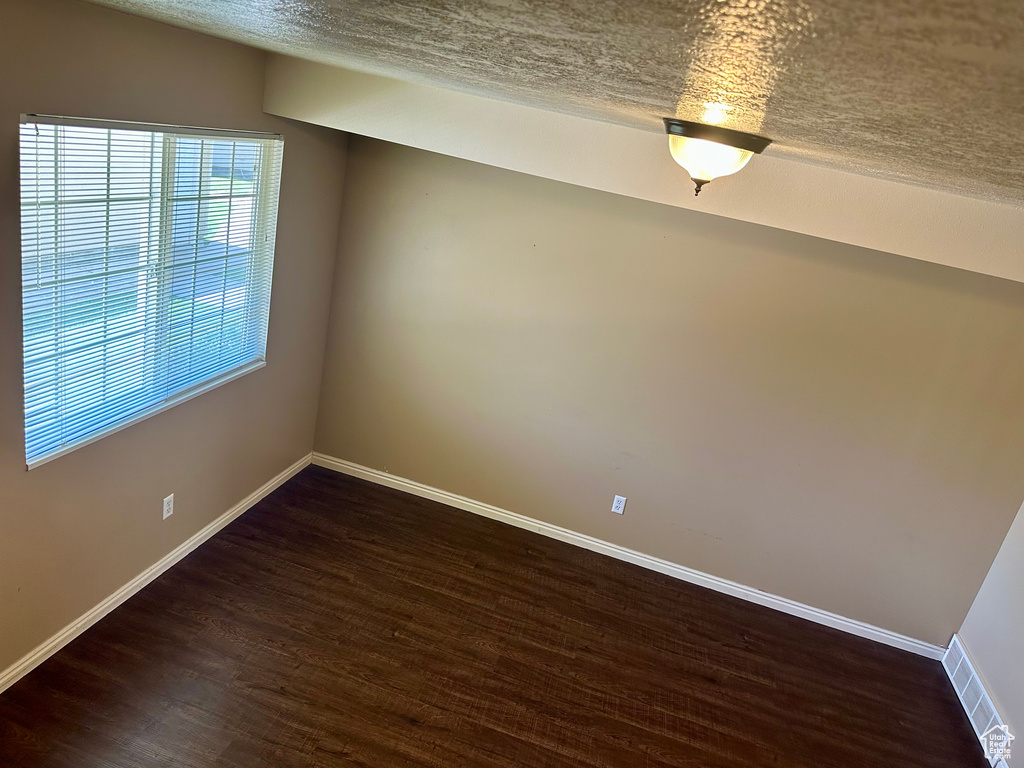 Unfurnished room featuring a textured ceiling and dark wood-style floors