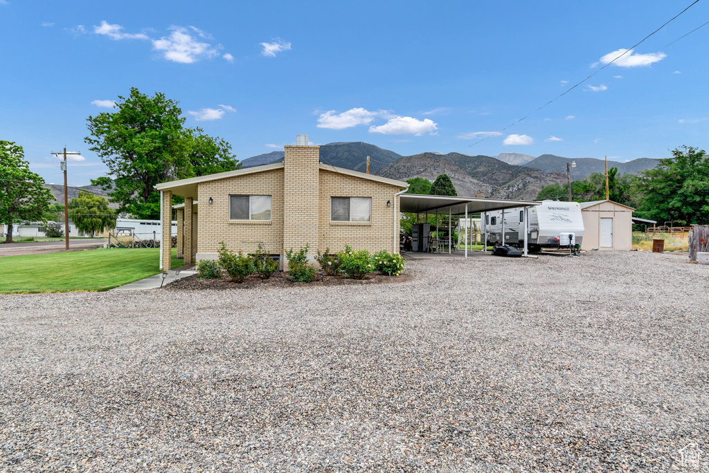 View of side of property featuring driveway, a mountain view, a carport, a chimney, and brick siding