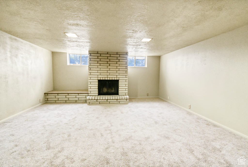 Below grade area with a fireplace, a textured ceiling, and carpet floors