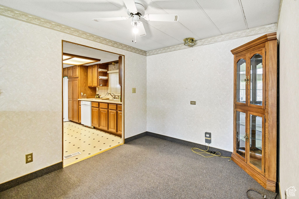 Empty room with light colored carpet, a sink, and a ceiling fan