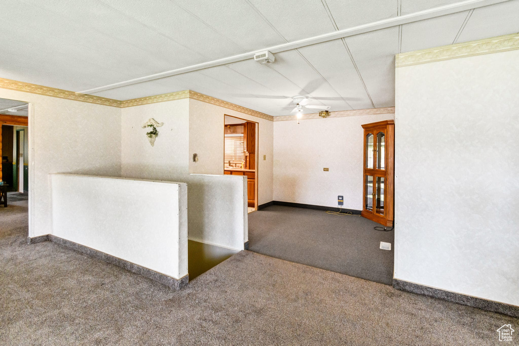 Carpeted spare room featuring a ceiling fan and baseboards