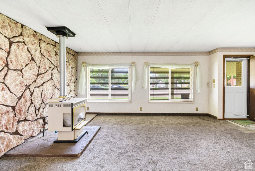 Unfurnished living room with a wood stove and carpet