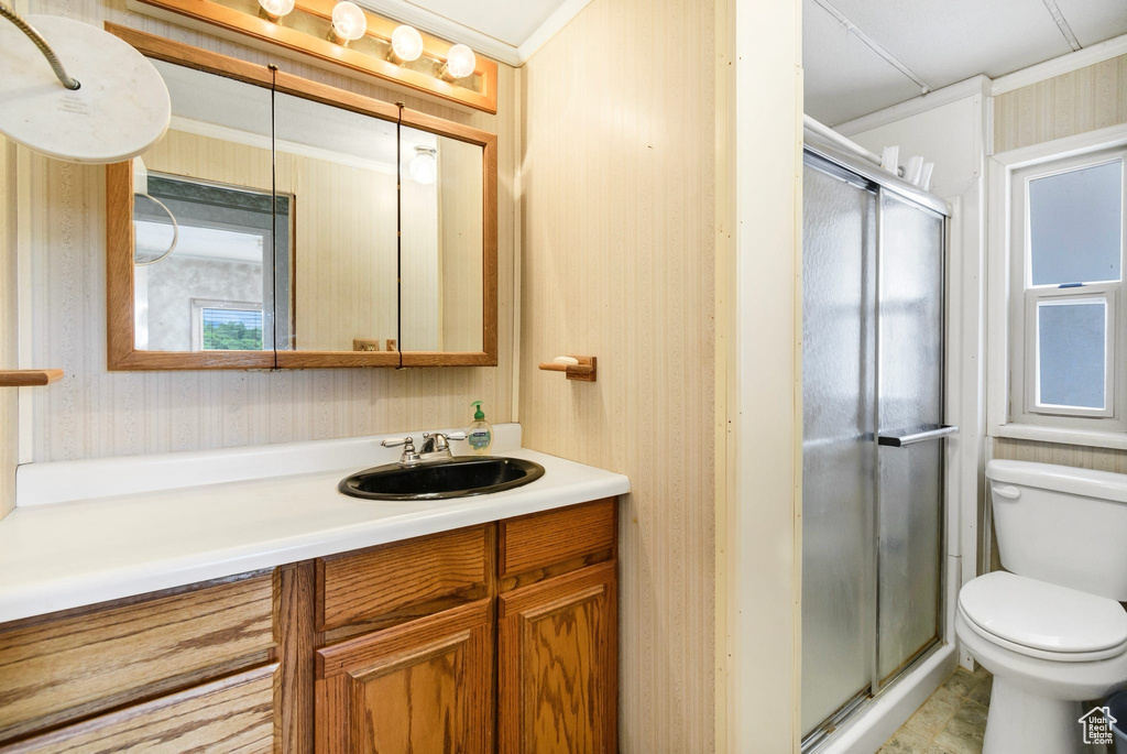 Bathroom featuring wallpapered walls, toilet, vanity, a shower stall, and crown molding