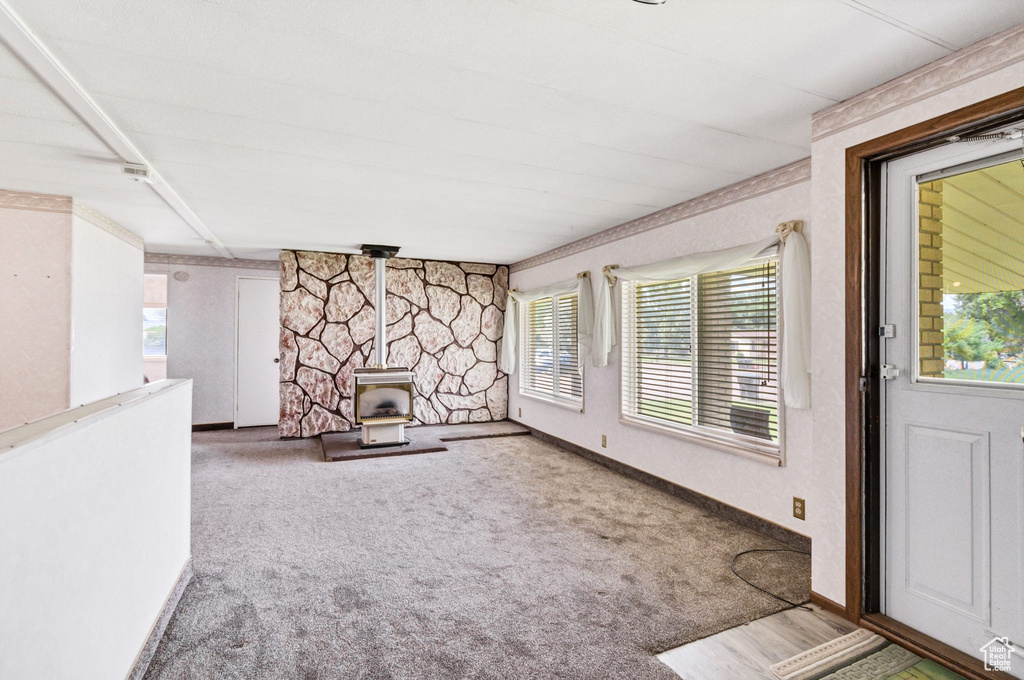 Unfurnished living room with a wood stove, carpet, and baseboards