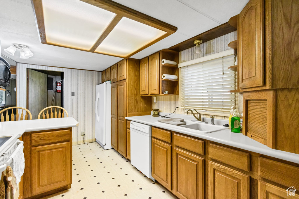 Kitchen with white appliances, a sink, light floors, open shelves, and brown cabinets