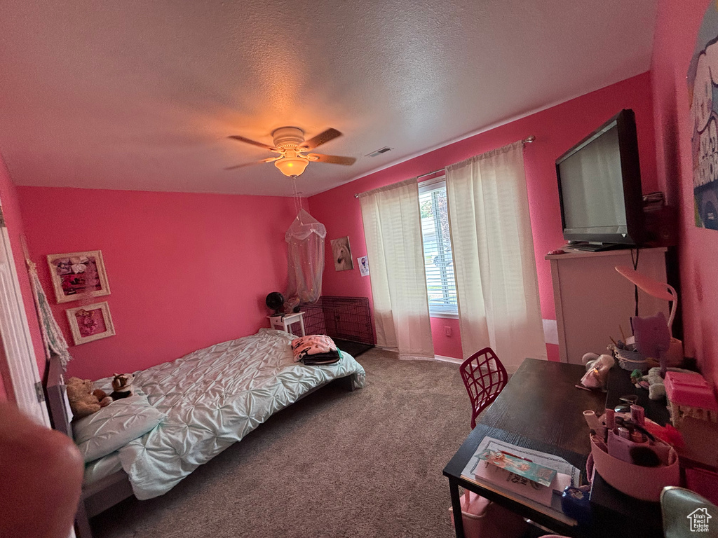 Carpeted bedroom featuring ceiling fan and a textured ceiling