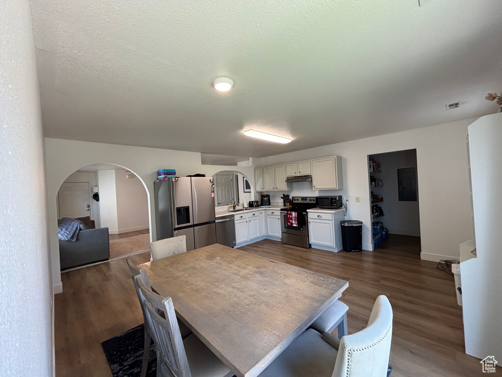 Dining space featuring arched walkways, dark wood-style flooring, baseboards, and a textured ceiling