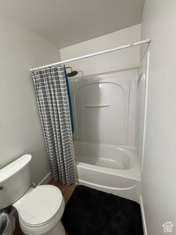 Full bathroom with toilet, shower / tub combo, and wood finished floors