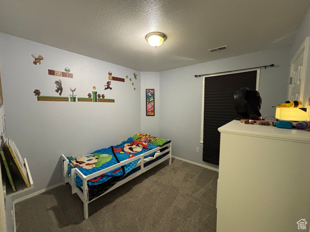 Bedroom with carpet, a textured ceiling, and baseboards