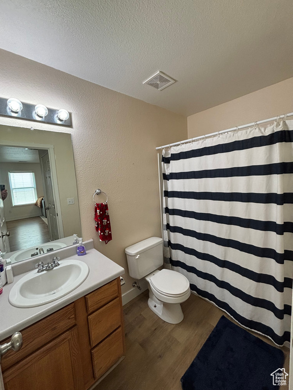 Full bath with toilet, wood finished floors, vanity, a textured ceiling, and a shower with shower curtain