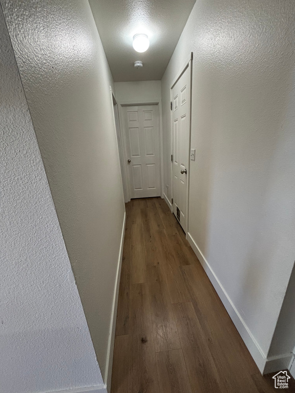 Hallway featuring dark wood-style flooring and baseboards