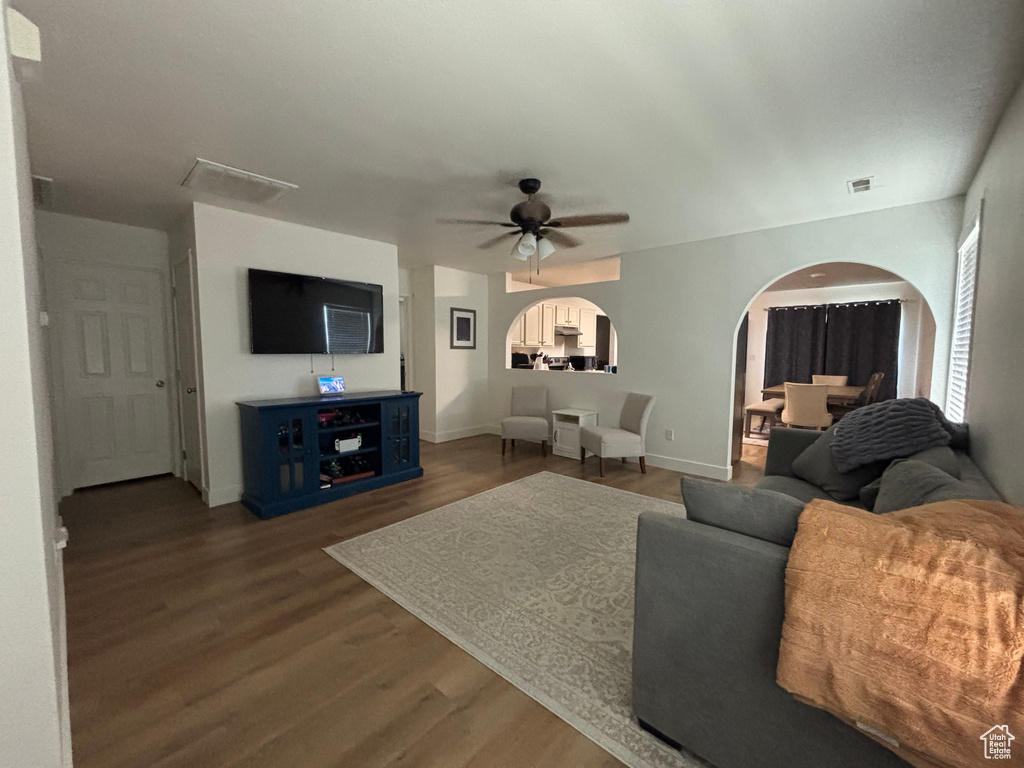 Living room featuring arched walkways, wood finished floors, ceiling fan, and baseboards
