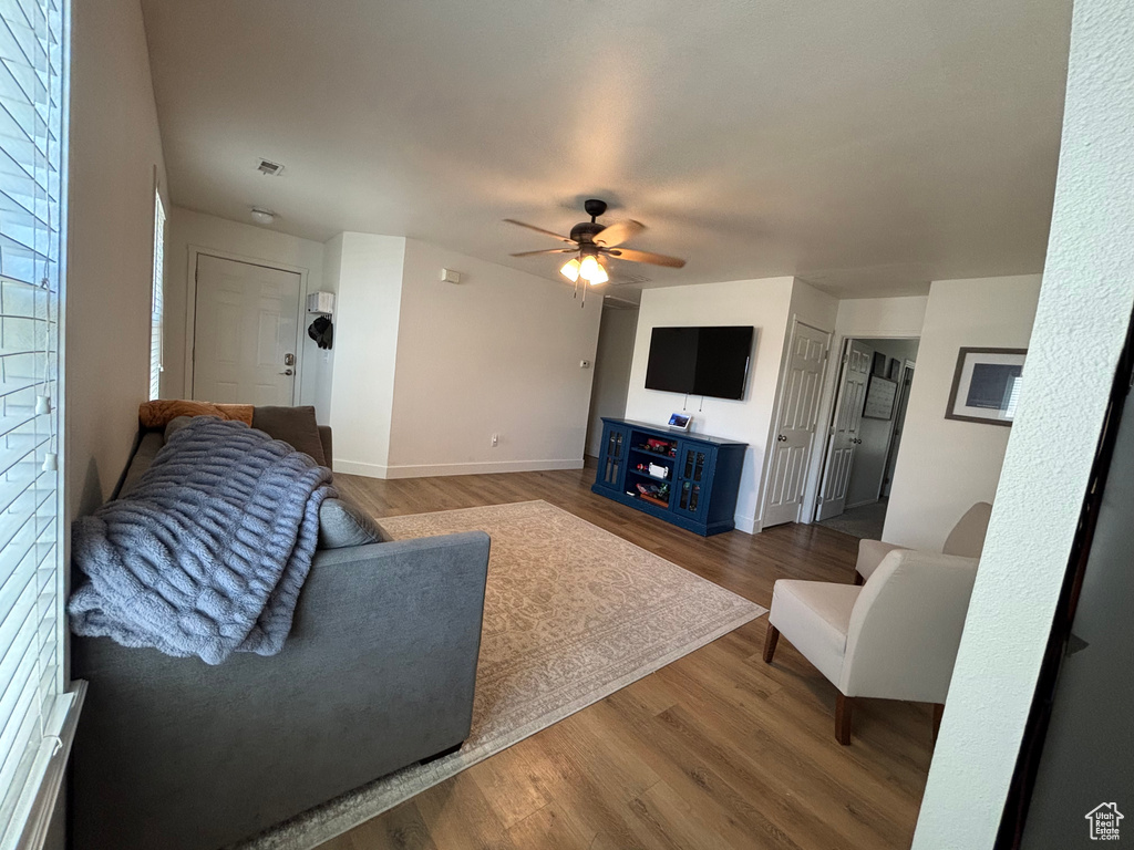 Living area featuring wood finished floors, a ceiling fan, and baseboards