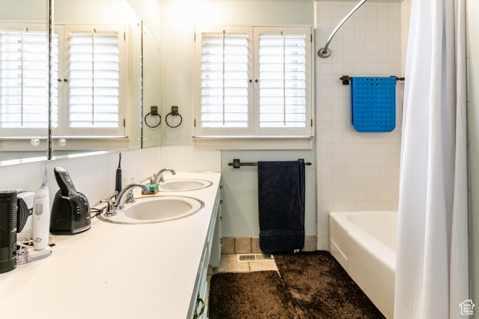 Bathroom with double vanity, plenty of natural light, and shower / tub combo