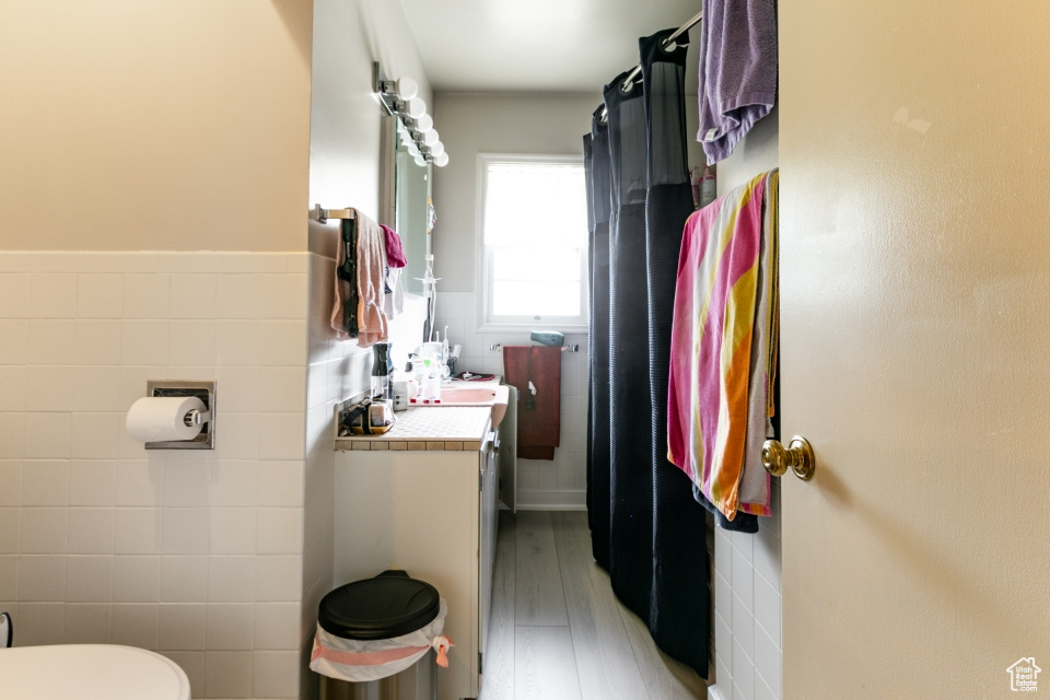 Bathroom with tile walls, wood finished floors, and vanity