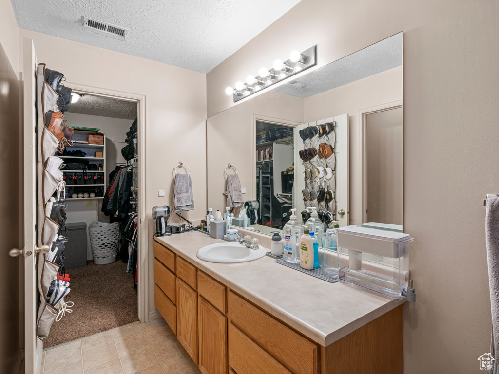 Bathroom featuring vanity, a textured ceiling, a spacious closet, and tile patterned flooring
