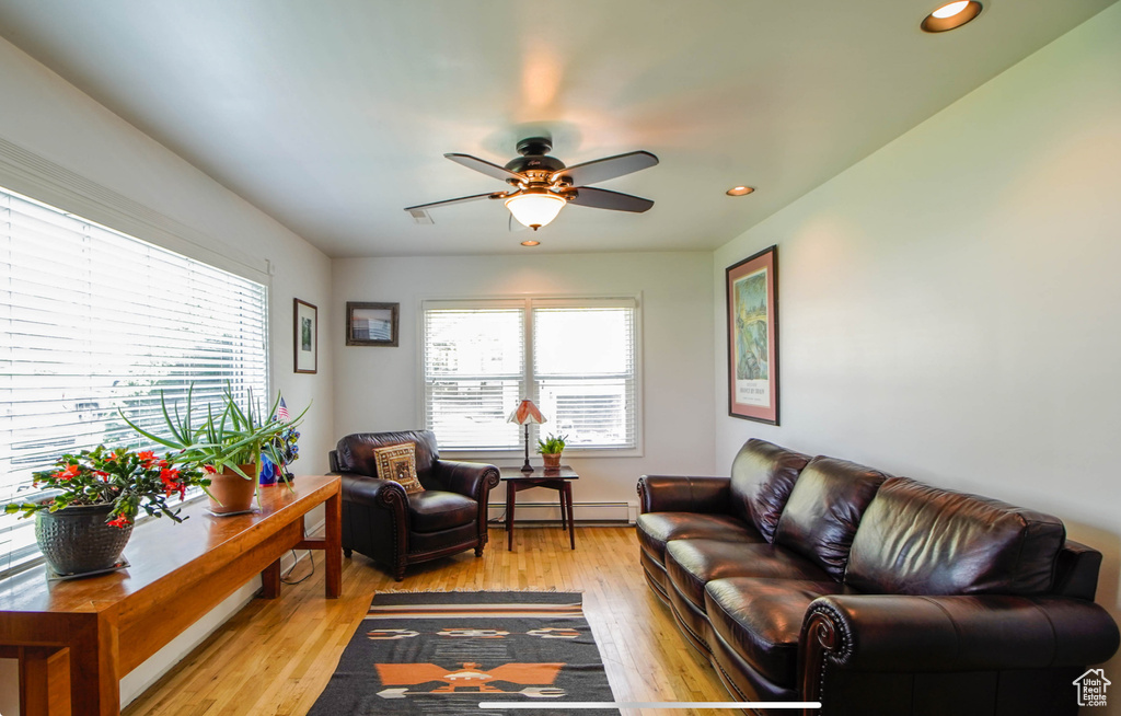 Living area with healthy amount of natural light, a ceiling fan, recessed lighting, and light wood-style floors